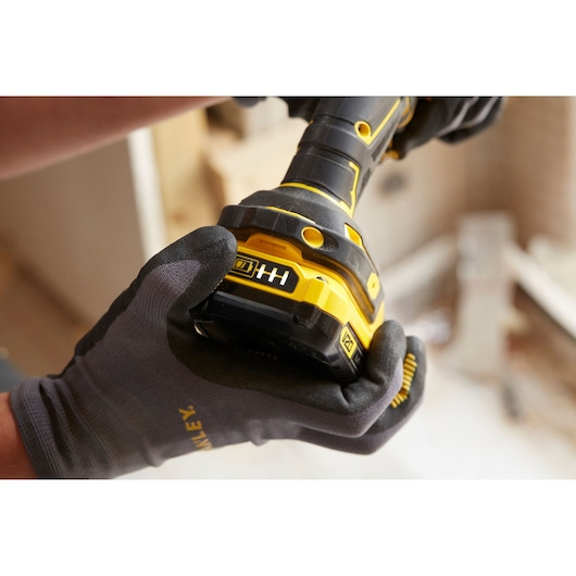 STANLEY SFMCD720B cordless drill close-up held by gloved hand, yellow and black body visible.