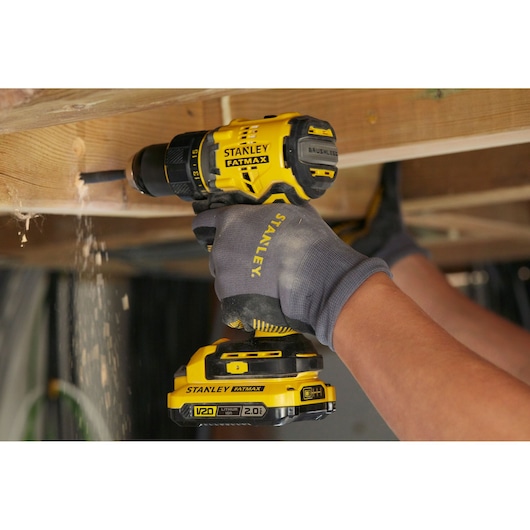 STANLEY SFMCD720B cordless brushless drill used for wood drilling, yellow and black, close-up action.
