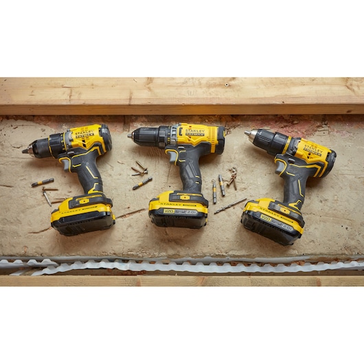 STANLEY SFMCD720B cordless drills in yellow and black, top view on concrete with bits and screws.