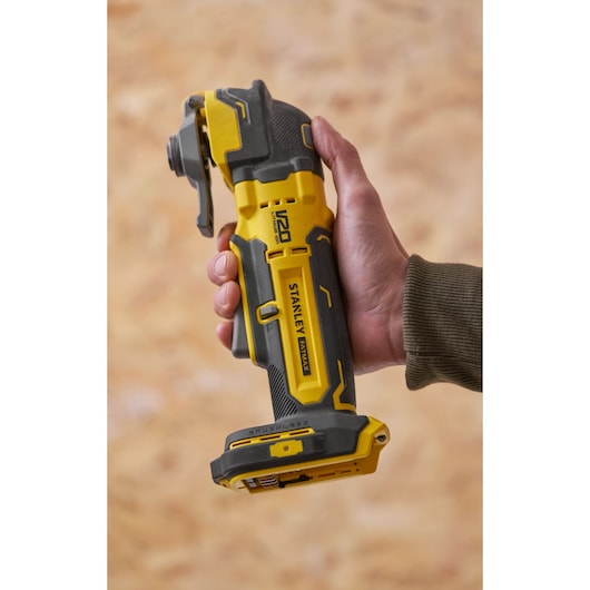 Photo of STANLEY SFMCE510B cordless multi-tool, yellow and black, held in a hand, side angle.
