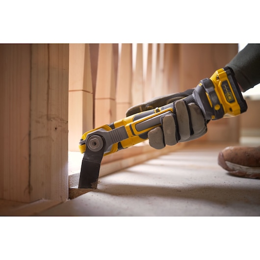 STANLEY SFMCE510B oscillating tool in use, yellow and black design, cutting wood near flooring.