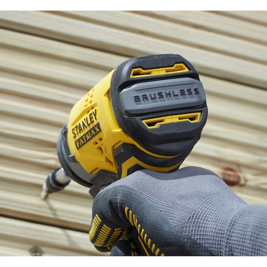 STANLEY SFMCF810B brushless impact driver held by gloved hand, close-up outdoor angle.