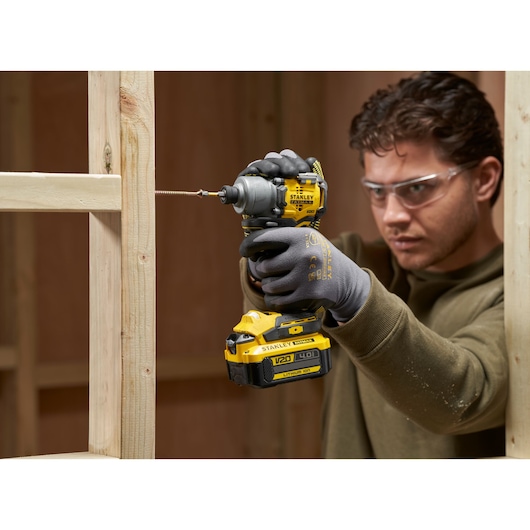 STANLEY SFMCF830B impact driver used in construction, close-up showing tool driving screw into wood.