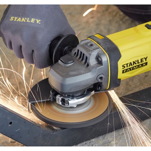 STANLEY SFMCG400B angle grinder cutting metal, yellow and black, sparks flying, close-up.