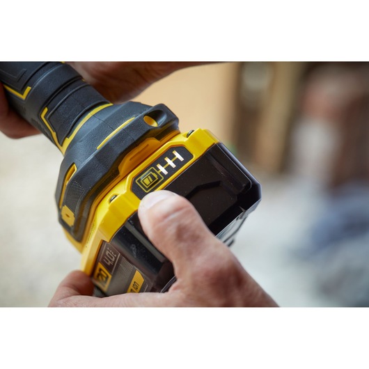 Close-up photo of hands holding STANLEY SFMCG400B cordless tool handle with visible battery indicator.