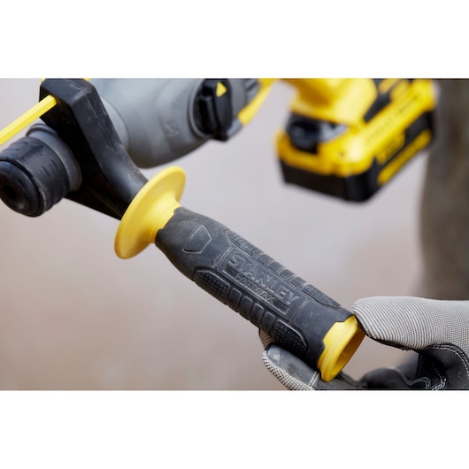 Photo of STANLEY SFMCH900B power tool handle with black and yellow grip, close-up view, gloved hand holding.