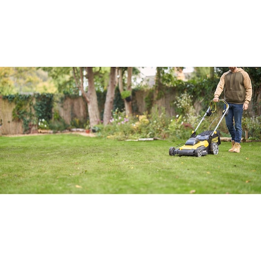 Photo of STANLEY SFMCMWS251B lawn mower in use on garden lawn.