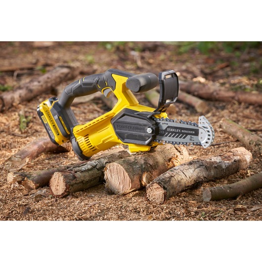 STANLEY SFMCPS415D1 cordless chainsaw photography, yellow and black, shown cutting logs outdoors.