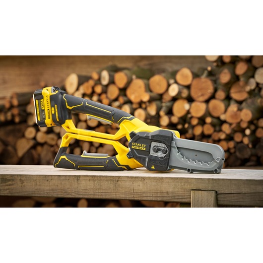 STANLEY SFMCPS515B cordless pruning saw with yellow and black body, displayed on wooden surface outdoors.