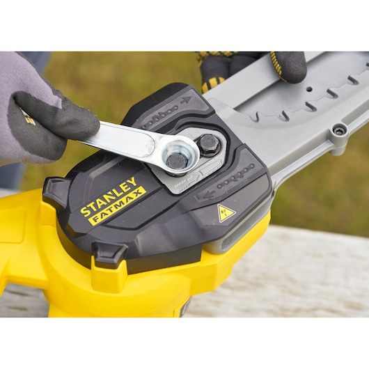 STANLEY SFMCPS515M1 chainsaw close-up, showing chain adjustment with wrench and glove.