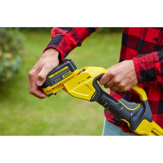 Photo of STANLEY SFMCPS620M1 yellow and black power tool handled outdoors, battery being inserted.