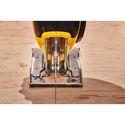 STANLEY SFMCS600B jigsaw cutting wood, front angle, yellow and black body, close-up photo.