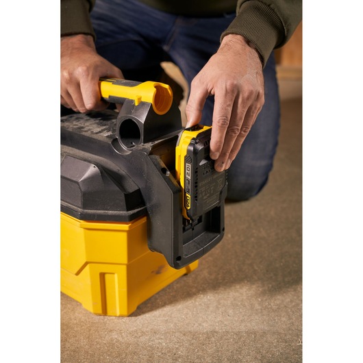 STANLEY SFMCV002B portable vacuum cleaner battery compartment close-up with person inserting battery.