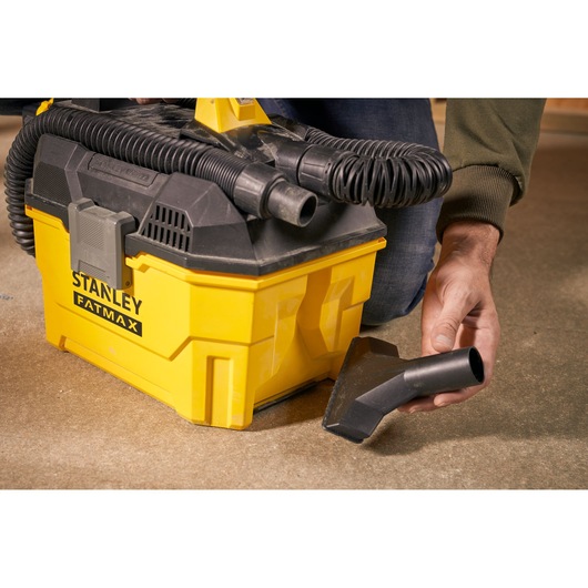 Photo of STANLEY SFMCV002B vacuum cleaner with yellow body, black hose, and accessory nozzle on floor.