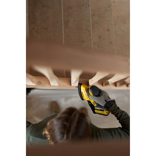 Photo of STANLEY SFMCW221B sander in use on a wooden staircase, hand holding tool for sanding railing.