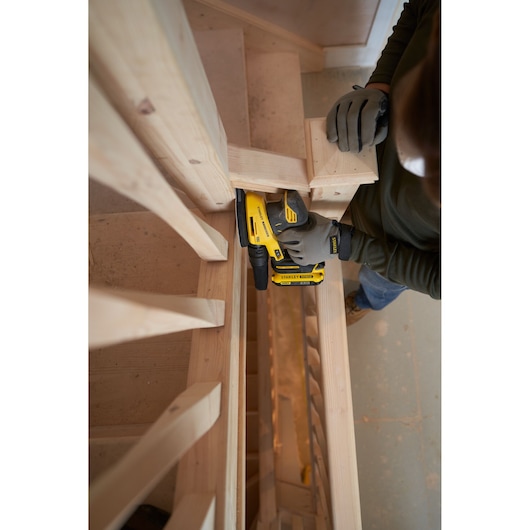 STANLEY SFMCW221B sander used on wooden stairs, close-up angle, operator wearing gloves.