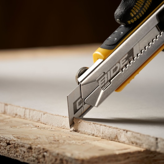 STANLEY STHT0-11825 utility knife cutting drywall, close-up, with silver blade and yellow handle.