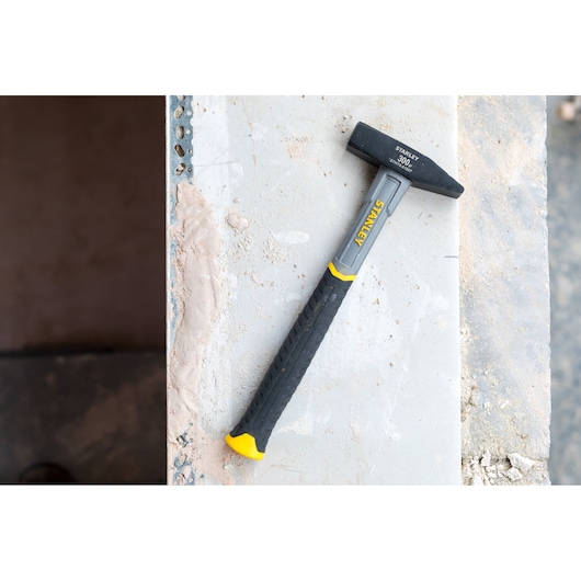 Photo of STANLEY STHT0-51907 club hammer with black and yellow handle on a construction surface.
