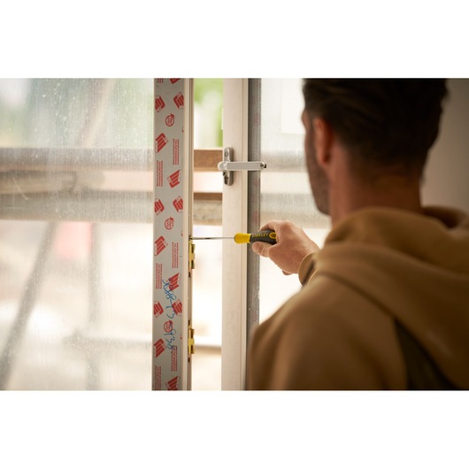 Photo of STANLEY STHT0-60335 screwdriver in use installing a window lock, held by a person in indoor setting.
