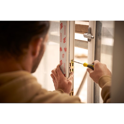 STANLEY STHT0-60335 screwdriver used for hinge installation on a door frame, close-up photography.