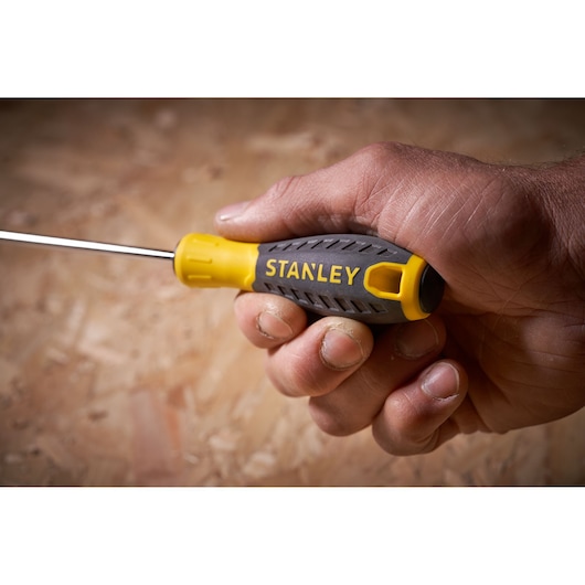 STANLEY STHT0-60335 screwdriver with yellow and gray handle held in a hand, side angle.