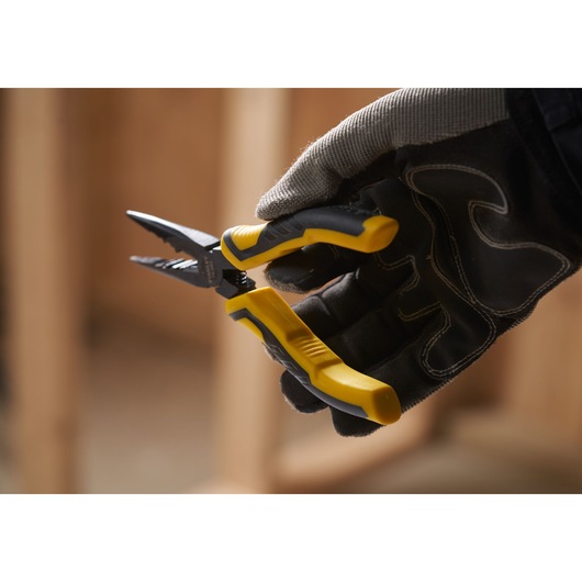 STANLEY STHT0-74363 wire stripper pliers with yellow handles held in a gloved hand, close-up photo.