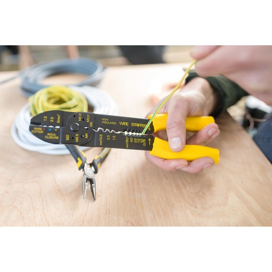 Photo of STANLEY STHT0-75414 wire stripper with yellow handles stripping wire on a workbench.