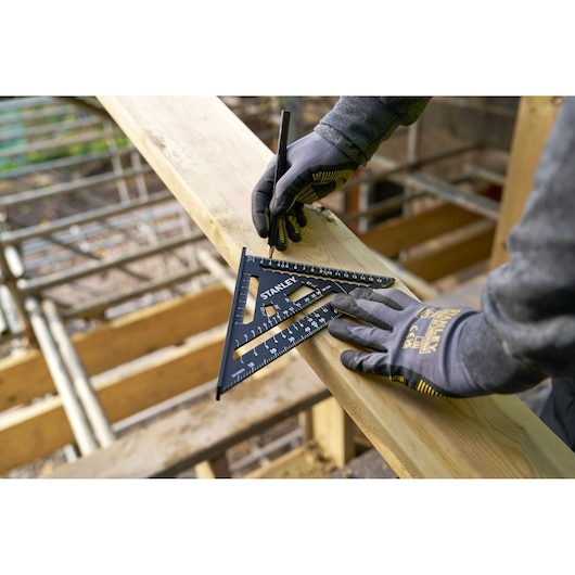 STANLEY STHT46101-0 carpenter's square for marking wood, gloved hands, outdoor construction.