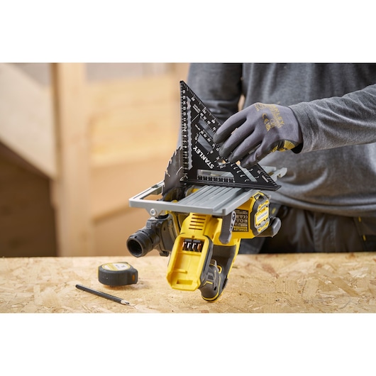 STANLEY STHT46101-0 black speed square in use on a saw table with pencil and tape measure on wooden surface.