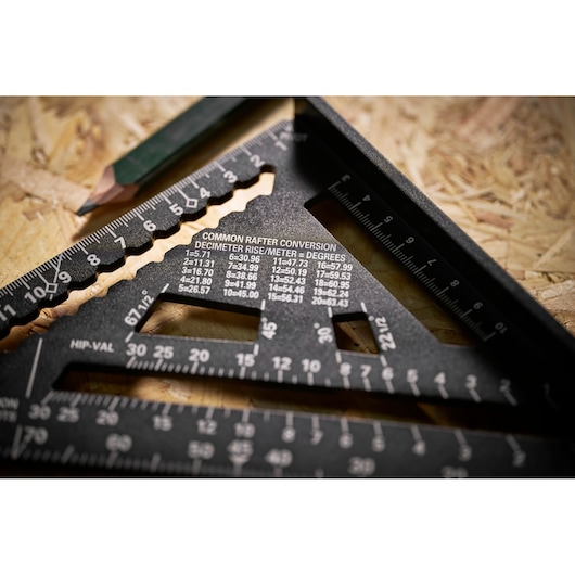 STANLEY STHT46101-0 photography of black rafter square with conversion tables, wood surface, pencil in background.