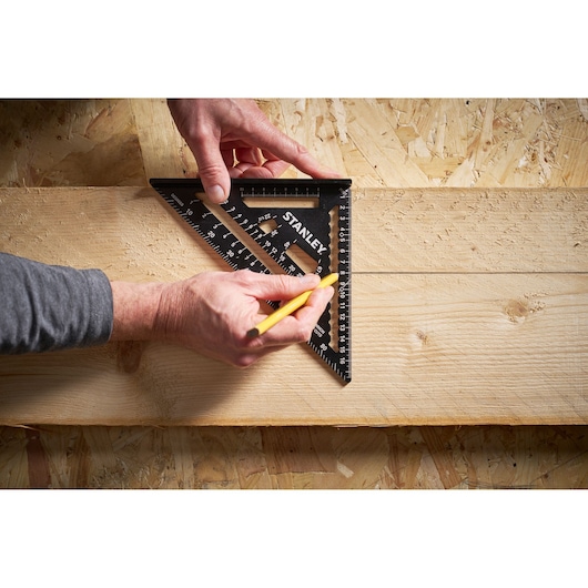 STANLEY STHT46101-0 black speed square used for marking on wood, close-up photography.