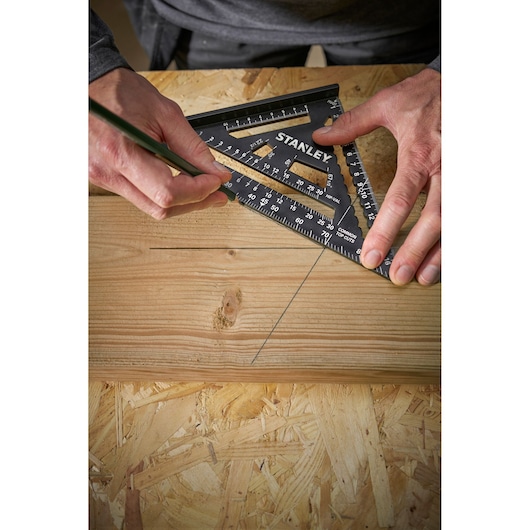 STANLEY STHT46101-0 black plastic speed square used to mark lines on wood, close-up photography.