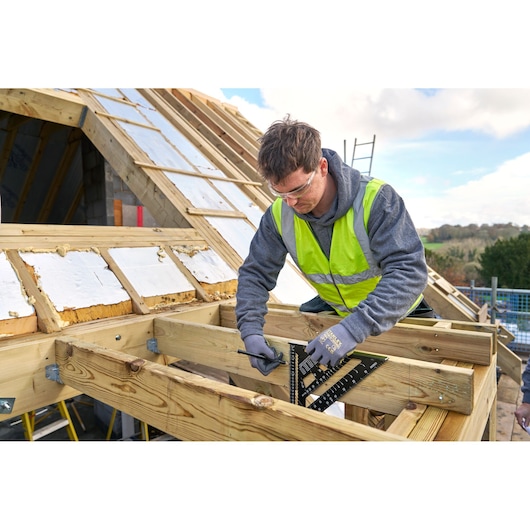 STANLEY STHT46102-0 roofing square used by a worker for wood measurement on construction site.
