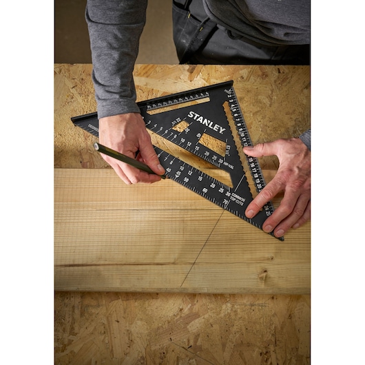 Photo of STANLEY STHT46102-0 black layout square used to mark a straight line on a wooden board.
