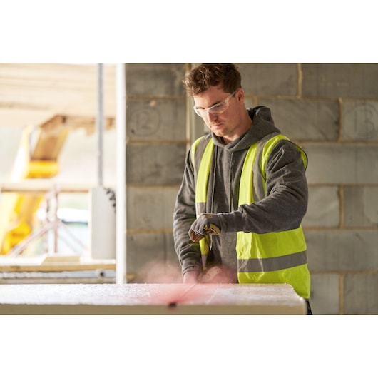 STANLEY STHT47611-0 photography of construction worker in hi-vis vest using tool at building site.