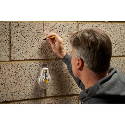 Photo of STANLEY STHT47611-0 chalk line being used to mark a vertical line on a concrete block wall.