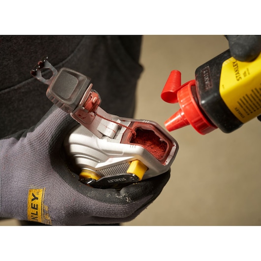 STANLEY STHT47611-0 chalk line being filled with red chalk powder, close-up view with gloved hand.