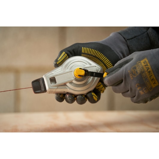 STANLEY STHT47611-0 chalk line reel held in gloved hands, outdoor construction setting.