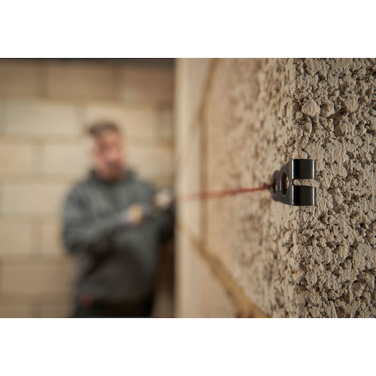 STANLEY STHT47611-0 masonry line holder in use on rough wall, close-up view, construction background.