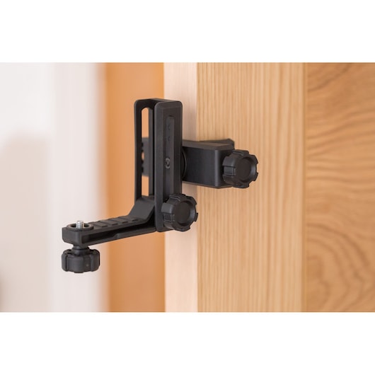 STANLEY STHT77594-1 black adjustable door clamp, mounted on wooden door, side view.