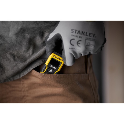 STANLEY STHT77666-0 laser measure being placed into pocket by gloved hand.