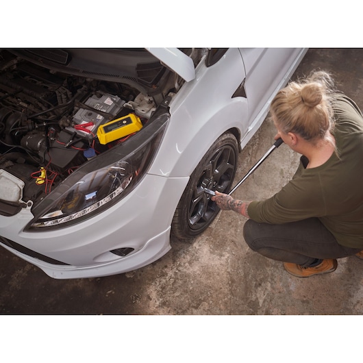 STANLEY STHT80890-0 photography of person using a wrench on car wheel with diagnostic tool on engine.