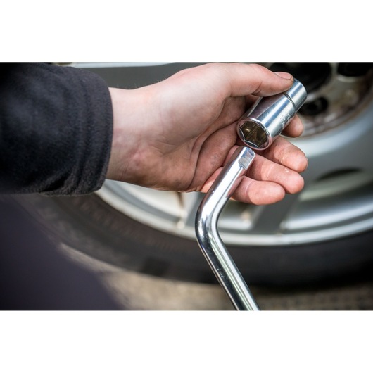 Photo of STANLEY STHT80890-0 socket wrench in hand near vehicle wheel, automotive tool in use.