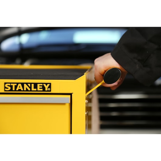 STANLEY STMT1-75063 yellow tool chest with drawer handle being pulled, close-up side angle.
