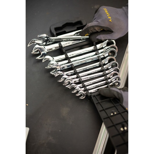 STANLEY STMT82847-0 ratcheting wrench set in holder, chrome finish, shown with gloved hands on black surface.