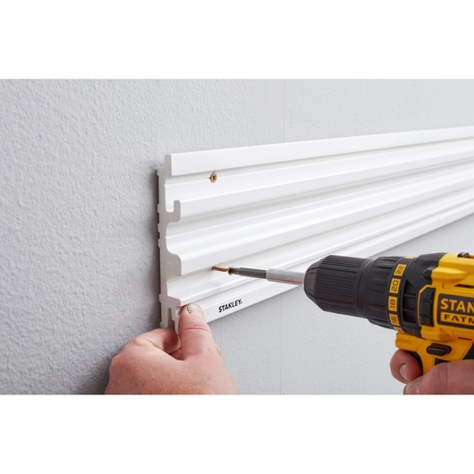 STANLEY STST82602-1 wall-mounted white storage rail, side angle, being installed with power drill.