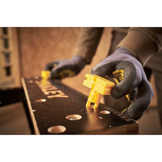 STANLEY STST83400-1 workbench with yellow clamp, close-up photography of gloved hands adjusting clamp.
