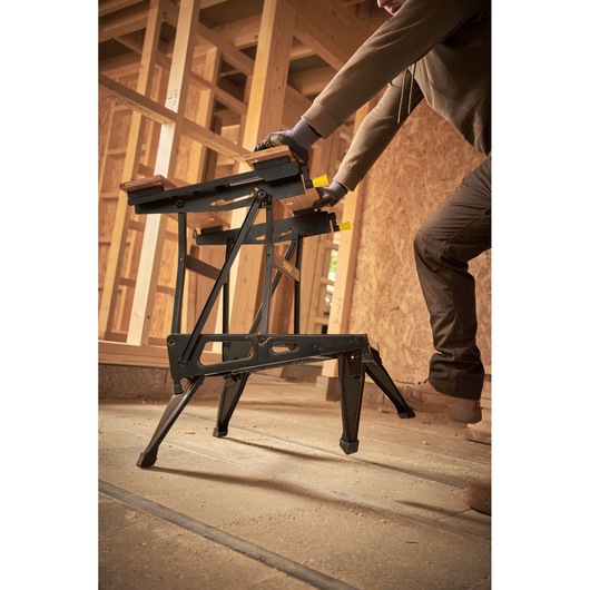 STANLEY STST83400-1 folding sawhorse in use at a construction site, black frame, wood panels on top.