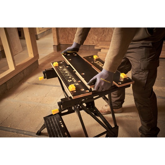 Photo of STANLEY STST83400-1 workbench in use in a workshop, black and yellow portable work table.